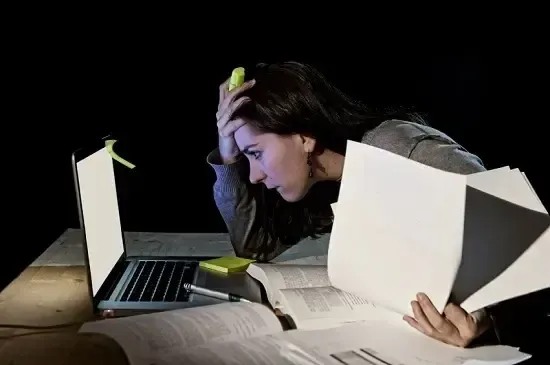 Mulher pensativa olhando para o notebook, frustrada com a falta de organização nos estudos
